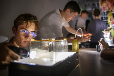 Mehrere Jugendliche experimentieren in einem abgedunkelten Raum
