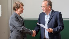 Prof. Moessner überreicht eine Urkunde an Prof. Prosen