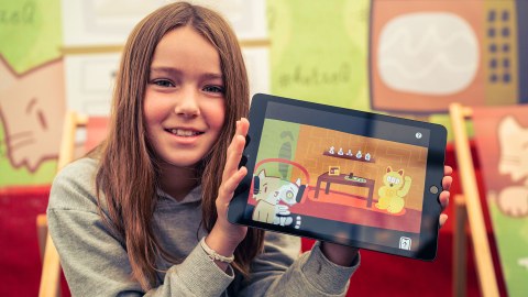 Ein Mädchen hält ein Tablet mit einem Computerspiel