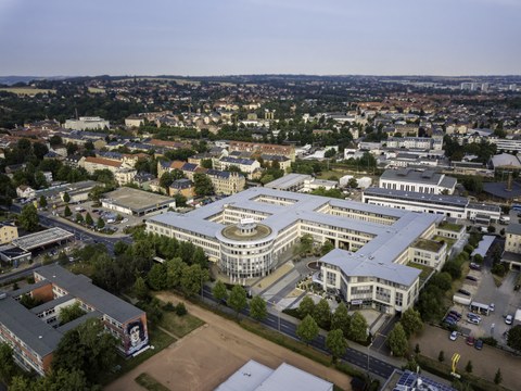 Das Foto zeigt eine Luftaufnahme des Gebäudekomplexes am Falkenbrunnen. Von oben betrachtet bildet das Gebäude ein Viereck mit einem Kreuz in der Mitte.