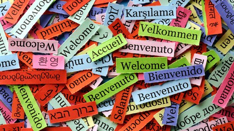 bunte Zettel mit dem Text Willkommen! in verschiedenen Sprachen
