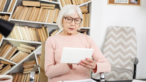 Lesende Seniorin im Arbeitszimmer