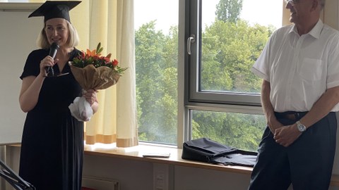 Rede von Dr. Rothländer (links) nach der erfolgreichen Promotion, mit dem Blumenstrauß