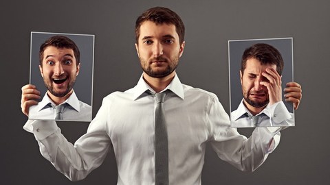 Ein Mann hält verschiedene Bilder mit Gesichtsaudrücken in der Hand.