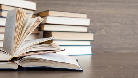 Auf dem Foto liegen zwei aufgeschlagene Bücher auf einem Tisch. Im Hintergrund ist ein Bücherstapel zu sehen