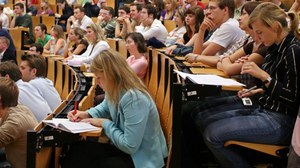 Studierende schreibe eine Klausur im Hörsaal