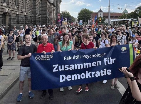 Mehrere Mitglieder der Fakultät Psychologie der TUD laufen auf einer Demonstration mit und tragen ein Banner mit der Aufschrift "Zusammen für Demokratie"
