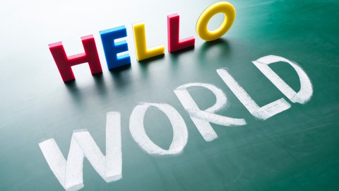 Das Foto zeigt eine Tafel, auf welche das Wort "world" mit weißer Kreide geschrieben wurde. Darüber ist mit Magnetbuchstaben das Wort "hello" dargestellt.