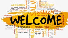 Die Darstellung zeigt das Wort "Welcome". Dieses befindet sich groß in der Mitte und ist gelb markiert. Drum herum befinden sich die Übersetzungen des Wortes in vielen verschiedenen Sprachen. 