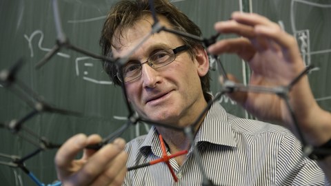 Ben Feringa, Chemie-Nobelpreisträger, hält ein Molekülmodell in die Kamera.