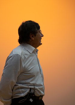 Halbprofil von Andre Geim vor orange beleuchteter Wand.