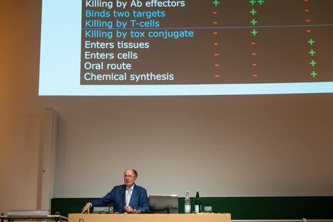 Mann am Pult mit Powerpoint im Hintergrund