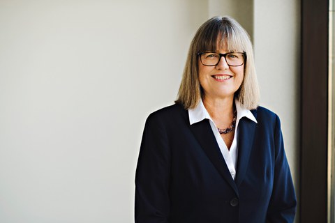 Eine Frau mit halblangen blinden Haaren und Brille. Sie lächelt freundlich. 