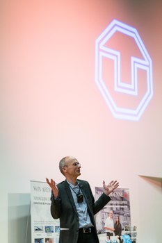 Prof. Dr. Carsten Timm vor dem Werbestand der Sponsoren "VON ARDENNE" Im Hintergrund wird das TU Logo mit einem Scheinwerfer an die Wand projizieren