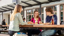 Studierende sitzen im Außenbereich der Mensa