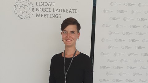 Janine Richter mit dem Logo der Lindauer Nobelpreistagung im Hintergrund.