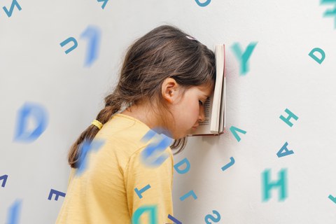 Mädchen lehnt sich mit Buch an die Wand.