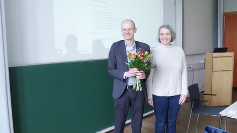 Ein Mann und eine Frau stehen vor einer Tafel.