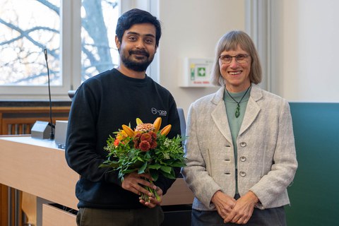 Preisübergabe. Die beiden Personen lächeln in die Kamera.