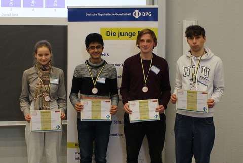 Vier Studierende mit einer Urkunde in der Hand.