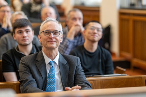 Hinter einem Mann sitzen viele Menschen im Hörsaal