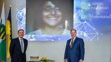 Prof. Klauss und Oberbürgermeister auf der Bühne, im Hintergrund Videoübertragung von Preisträgerin Shreenanda Gosh