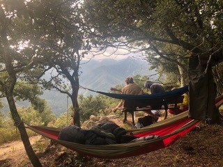 Eine Mann in einer Hängematte in einer bewaldeten Landschaft.