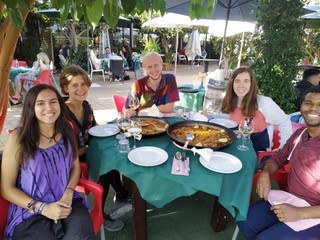 Mehrere Personen sitzen am gedeckten Tisch und lachen in die Kamera.