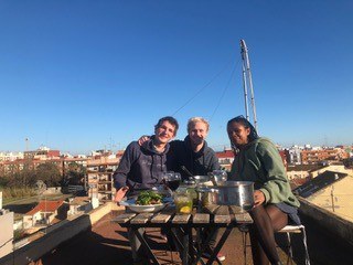 Drei Personen sitzen am Tisch und lachen in die Kamera.