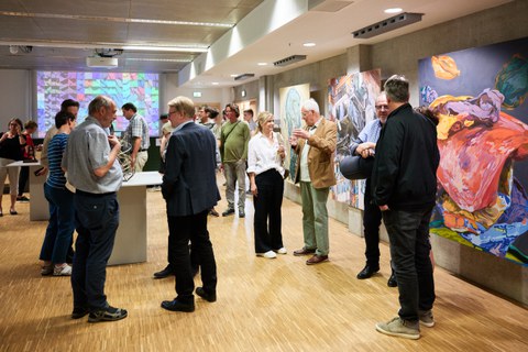 In einer Galerie stehen viele Menschen und unterhalten sich