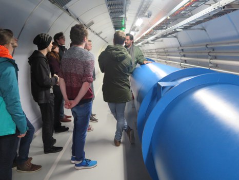 Die Studierenden neben einem Modell des LHC.