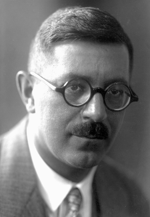 Porträt eines Mannes mit Brille und Schnauzbart.