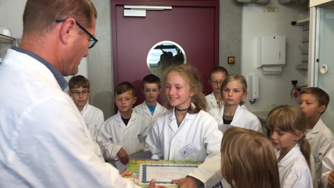 Der Leiter des Kinderlabors, Dr. Uwe Schwarzenbolz, zeichnet die 10-jährige Grundschülerin Josefine Bohn als 2.000 Teilnehmerin des Kinderlabors aus. 