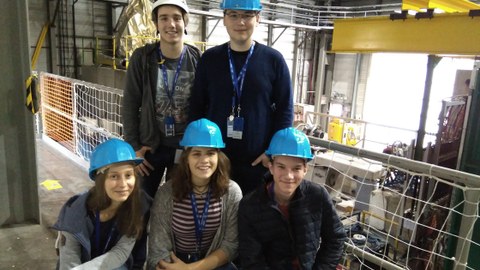 Fünf Jugendliche posieren mit Schutzhelmen auf den Köpfen vor dem Hintergrund des Compass-Experiments