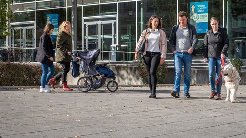 Bild mit einer Gruppe Studierender mit Kinderwagen und Blindenund.