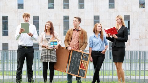 Das Foto zeigt fünf Personen, welche auf einer Wiese vor dem Gebäude der SLUB stehen. Drei Personen halten Bücher in der Hand. Eine Person in der Mitte hält eine Tafel mit der Aufschrift: "TU Dresden Geistes- und Sozialwissenschaften". 
