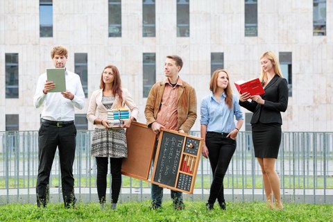 Das Foto zeigt fünf Personen, welche auf einer Wiese vor dem Gebäude der SLUB stehen. Drei Personen halten Bücher in der Hand. Eine Person in der Mitte hält eine Tafel mit der Aufschrift: "TU Dresden Geistes- und Sozialwissenschaften". 