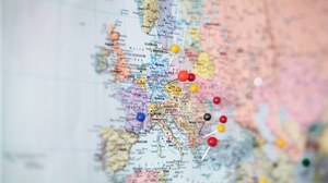  Das Foto zeigt eine Weltkarte, auf welcher der europäische Kontinent in den Fokus gerückt wurde. In einigen der Länder stecken Pinnadeln mit unterschiedlich farbigen Köpfen. 