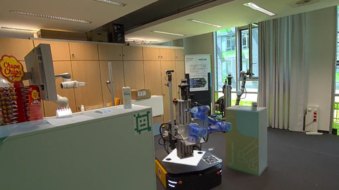 Autonomer Logistikroboter mit mobiler Plattform und Greifarm in einer Laborumgebung.