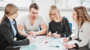 Vier Studierende arbeiten mit Karten auf einem Flipchart-Tisch