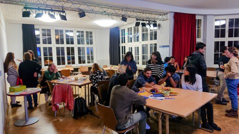 Foto von Teilnehmer:innen bei Gruppenarbeit am Tisch