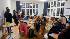 Foto von Teilnehmer:innen bei Gruppenarbeit am Tisch