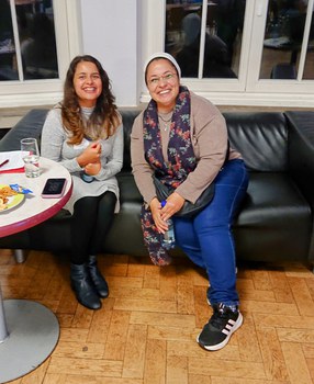 Foto von zwei in die Kamera lächelnden Personen bei der Veranstaltung auf einem Sofa