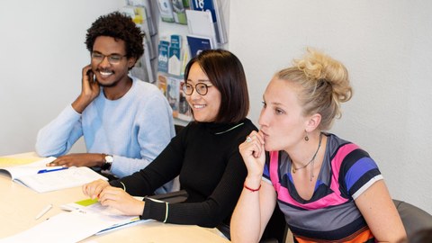 Foto von drei lächelnden Studenten im Career Service Workshop an der TU Dresden. 