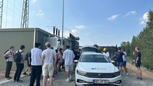 Auto mit umherstehenden Menschen im Umspannungswerk