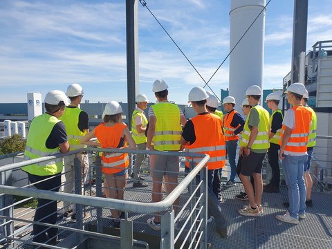 verschiedene Menschen mit Schutzhelm stehen auf einer Plattform