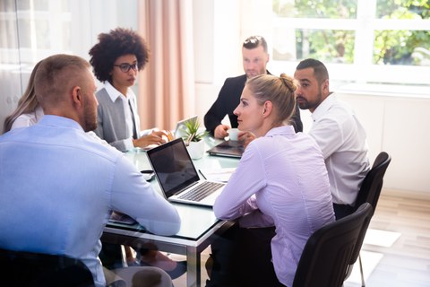 Team sitzt um einen Tisch und diskutiert