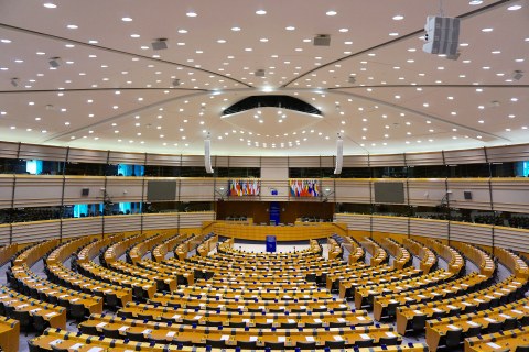 großer runder Saal mit vielen Sitzen, Rednerpult in der Mitte, dahinter verschiedene Länderflaggen