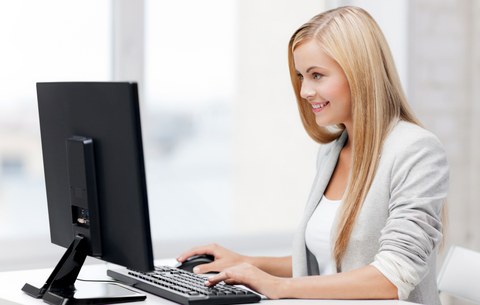 blonde Frau sitzt vor Computer