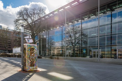 Foto vom Vorplatz des Hörsaalzentrums mit einer bunten Telefonzelle.